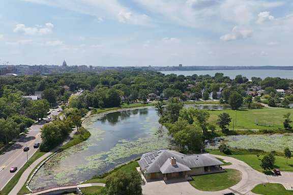 A serene landscape with a lake, a building, and a city skyline in the distance.