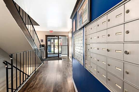 A hallway with a railing on the left and a row of mailboxes on the right.