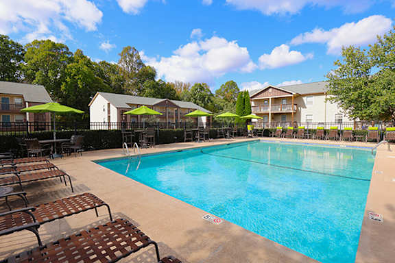 a resort style pool with chairs and umbrellas next to a building