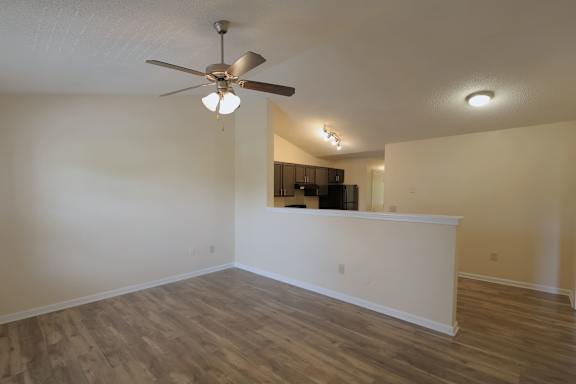 A room with a ceiling fan and wooden flooring.