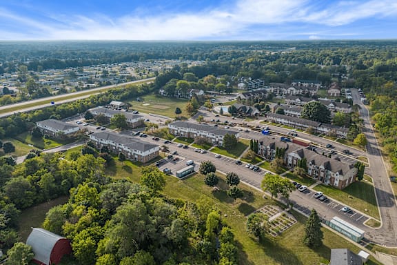 A bird's eye view of a residential area with houses, trees, and a parking lot.