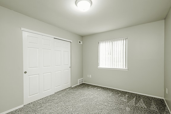A white door is on the left of a room with a window on the right.