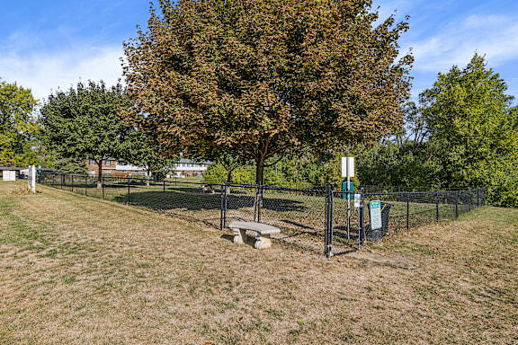 A tree in a field with a fence and a sign.