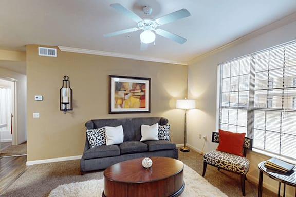 A living room with a grey couch and a painting on the wall.