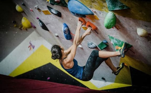 A person climbing a rock wall indoors.