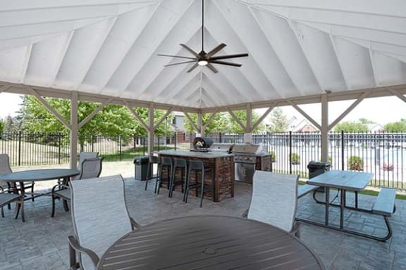 a patio with a table and chairs and a grill