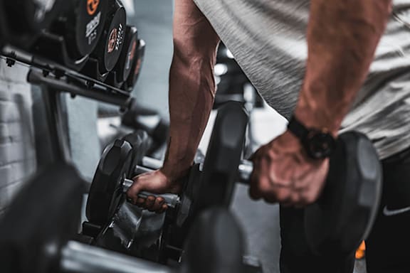 A man is working out with dumbbells in a gym.