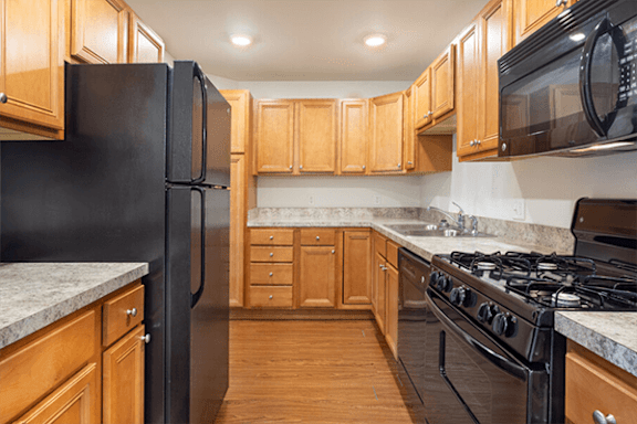 A kitchen with black appliances and wooden cabinets.