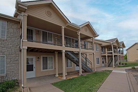 Apartment complex with stone pillars and a balcony.