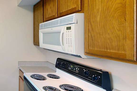 A white microwave oven is mounted above a stove.