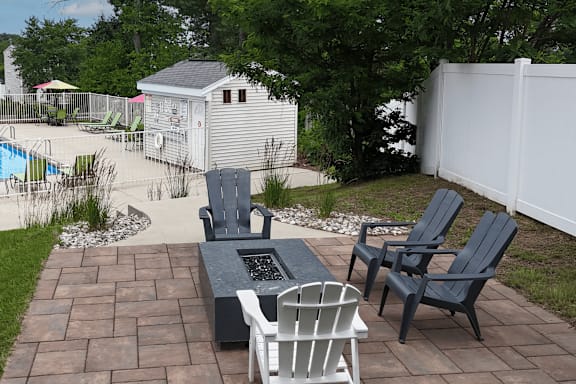 A backyard with a fire pit and chairs.