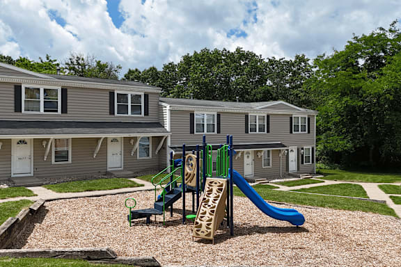 A playground with a slide and a swing set in front of a building.