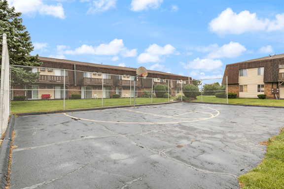 an empty basketball court in front of an apartment building