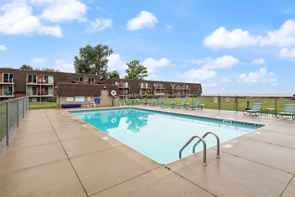 a swimming pool with chairs around it in front of a building