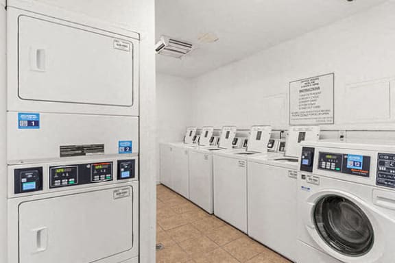 a row of washing machines and dryers in a laundry room