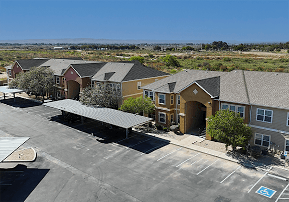 A parking lot with a few cars and a building in the background.