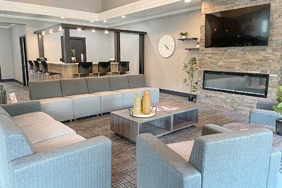 A living room with grey couches and a stone fireplace.