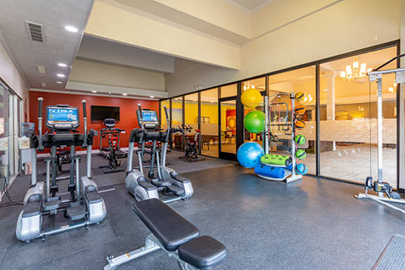 A gym with a variety of equipment including treadmills, exercise balls, and weight machines.