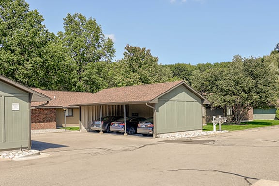 A carport with a brown roof and a garage door is in front of a house.