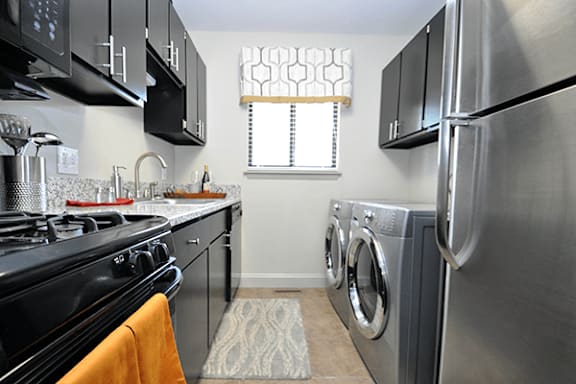 A modern kitchen with a black stove top oven and a washer and dryer in the laundry area.