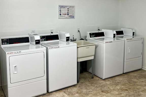 A white washing machine and dryer are in a room with a poster on the wall.