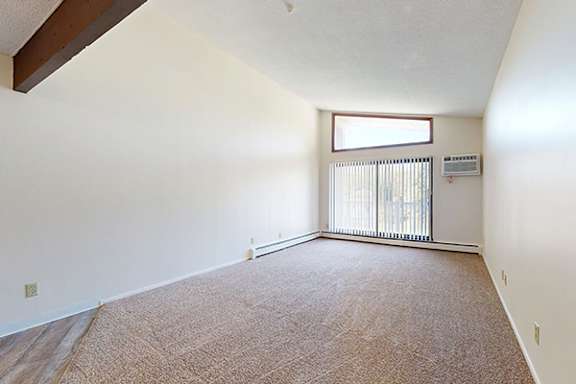A room with a carpeted floor and a window with blinds.