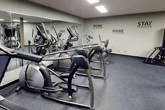 A gym with a row of treadmilers and a wall that says "Stay Positive".