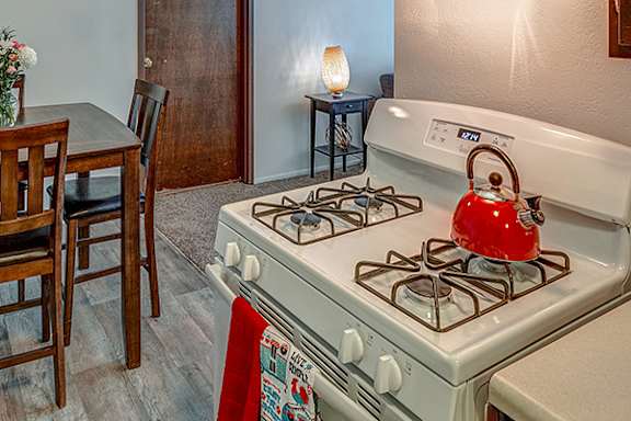 A red kettle is on a white gas stove.