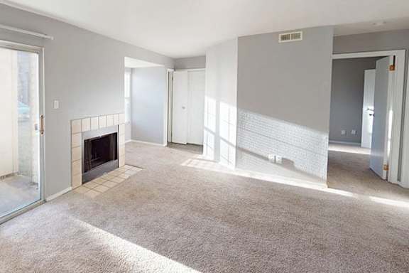 A living room with a fireplace and a carpet.