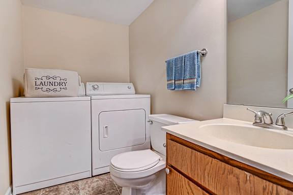 A laundry sign is on a cabinet next to a toilet in a bathroom.