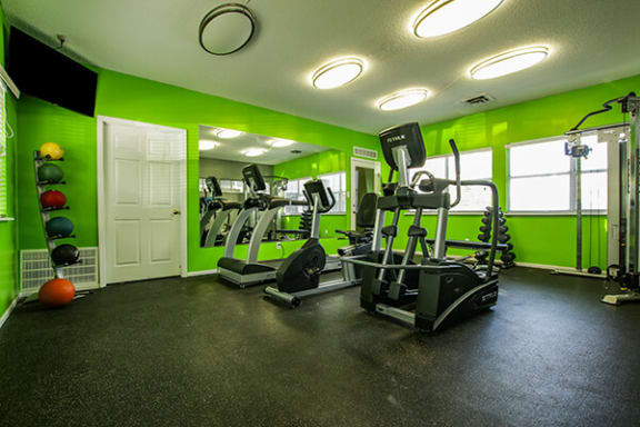 a gym with exercise equipment and green walls
