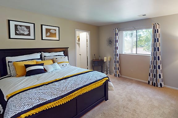 A bedroom with a large bed and a window with curtains.