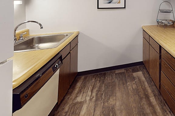 A kitchen with a wooden floor and a white wall.