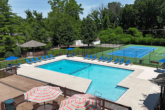 A pool with a tennis court and a gazebo.