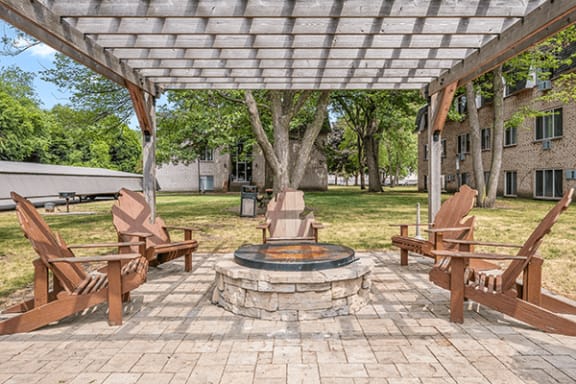 a patio with a fire pit and chairs