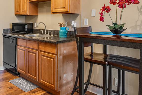 A kitchen with wooden cabinets and a black microwave.