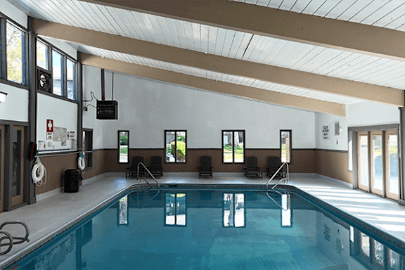 A large indoor swimming pool with a diving board and lane markers.