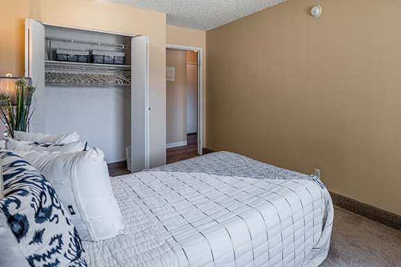 A bedroom with a bed, pillows, and a bunk bed in the background.
