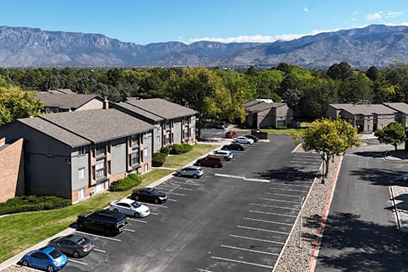 A parking lot with cars and apartment buildings in the background.