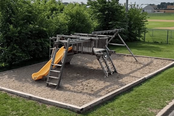 A playground with a yellow slide and a ladder.