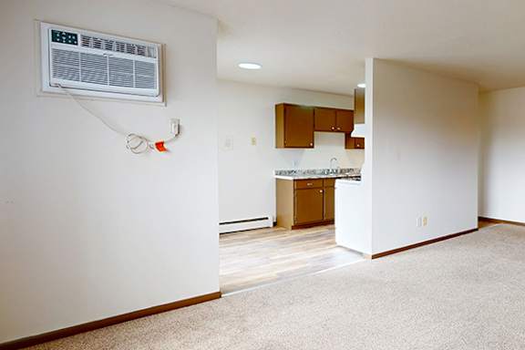 A room with a white wall and a window with a thermostat on it.