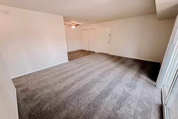 an empty living room with carpeting and white walls