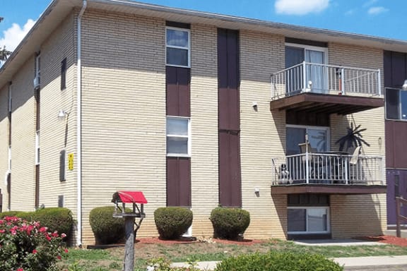 an apartment building with two balconies and a red awning