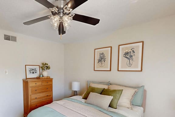 A bedroom with a bed, dresser, and two framed pictures on the wall.