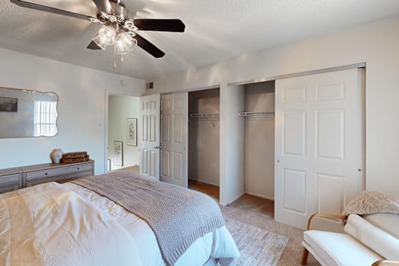 A bedroom with a large bed and a ceiling fan.