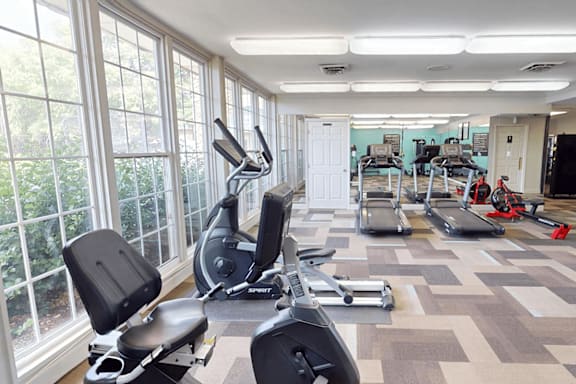A home gym with a variety of equipment including treadmills, stationary bikes, and weight machines.