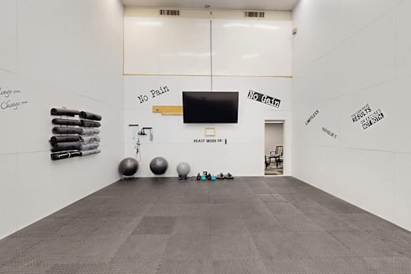 A room with a wall that says "No Pain No Gain" and a row of exercise balls.