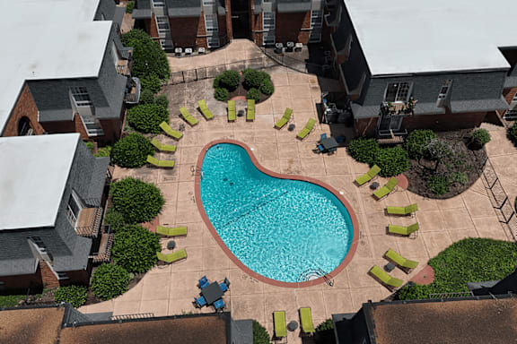 A heart-shaped pool surrounded by green bushes and yellow chairs.