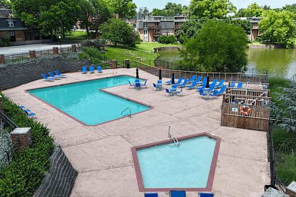 A large outdoor swimming pool with blue lounge chairs.
