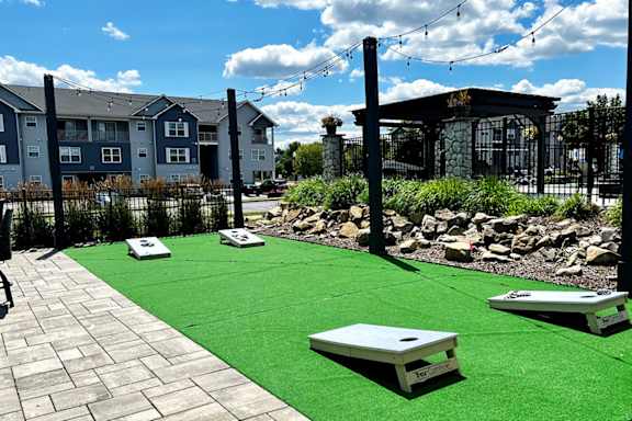 A shiny green lawn with a few white boards and a building in the background.